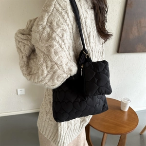 Borsa tote nera minimalista con trapuntatura a cuore e mini pochette vista laterale