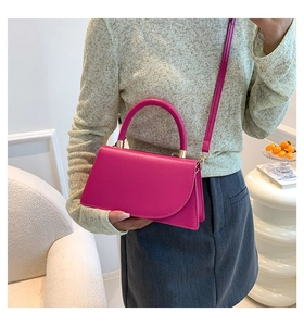 Detail of magenta faux leather crossbody bag with top handle and gold metal hardware