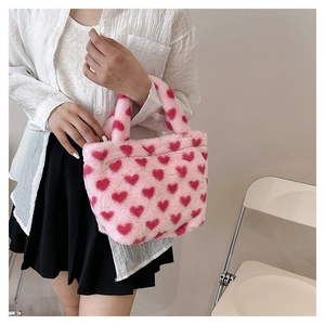 Close-up of pink plush handbag with red heart patterns and soft faux fur texture
