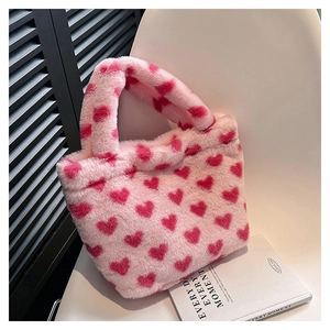 Detail of pink faux fur handbag featuring red heart patterns on a soft plush texture