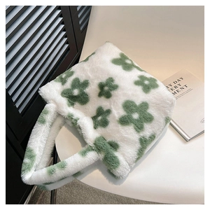 Close-up of fluffy white faux fur tote bag with green floral patterns on a chair