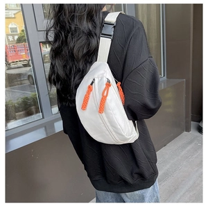 Close-up of white nylon chest bag with orange zipper pull and adjustable buckle strap