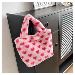 Close-up of soft pink plush tote bag with red heart patterns and fluffy dual handles