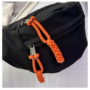 Close-up of black nylon bag with double metal zippers and bright orange cord pullers
