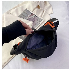 Close-up of black nylon chest bag with orange rope zipper and spacious inner lining