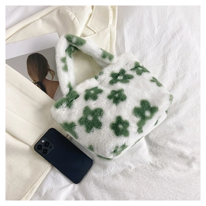 Detail of plush white faux fur handbag featuring green floral pattern on soft fabric