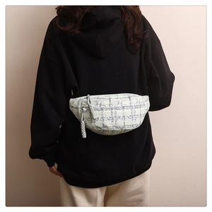 Gros plan d'un sac banane en tweed bleu et blanc avec tirette de fermeture tissée déco