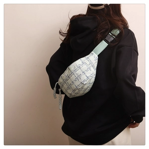 Détail du sac de poitrine en tweed bleu avec sangle verte et boucle de fermeture en plastique