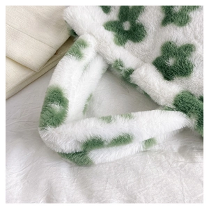 Close-up of white plush handbag with green flower pattern and thick soft fuzzy handles