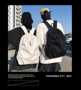 Rear view of black and beige minimalist backpacks worn by models in outdoor city setting