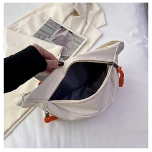 Detail of cream nylon waist bag interior with black lining and orange zipper cord