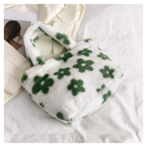 Close-up of white plush handbag featuring green floral patterns and soft fluffy texture