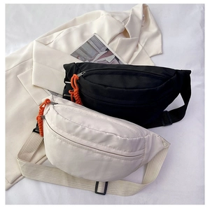 Close-up of black and off-white crossbody bags with nylon texture and orange zipper pulls