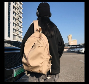 Outdoor shot of a beige minimalist nylon backpack showing large capacity and side pockets