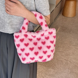 Pink fluffy plush handbag with red heart patterns for women in a cozy cafe setting