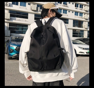Outdoor shot of a black urban techwear backpack with side adjustable drawstrings