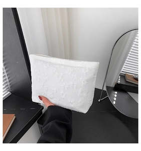 Detalle de bolso de mano blanco con textura floral en relieve y diseño minimalista