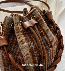 Detailed view of the plaid fabric texture and leather drawstring on this bucket bag