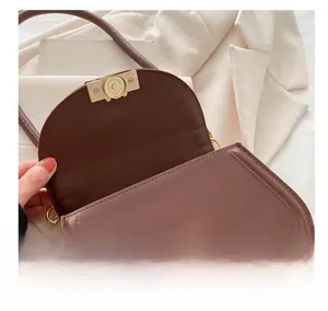 Dettaglio borsa in pelle marrone con chiusura magnetica dorata e incisione fine