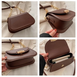 Dettaglio borsa in pelle marrone con fibbia a spirale dorata e tracolla a catena da quattro angoli