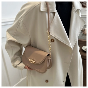 Dettaglio della borsa minimalista beige in similpelle con fibbia oro e tracolla a catena
