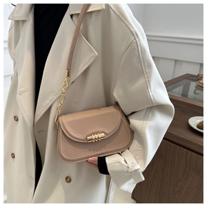Dettaglio della borsa a tracolla in pelle beige con chiusura dorata e catena metallica
