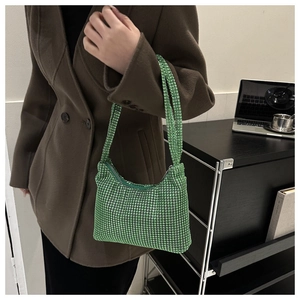 Detail der smaragdgrünen Strass-Schultertasche, getragen mit braunem Mantel im Büro