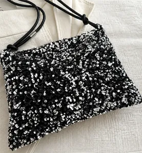 Dettaglio ravvicinato di paillettes nere e argento su borsa retrò con nodo sulla tracolla