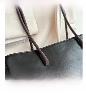 Detail of reinforced shoulder strap stitching on a black textured leather tote bag