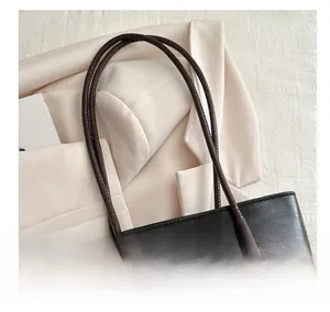 Close-up of black litchi leather tote bag with dark brown straps and stitching details