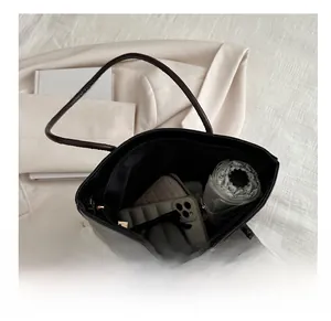 Top-down view of spacious interior of black leather tote bag with umbrella and essentials