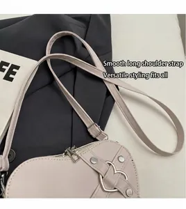 Détail d'un sac bandoulière en forme de cœur avec boucles en métal et sangle réglable