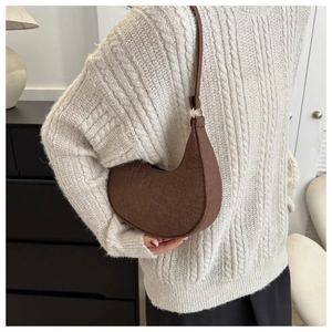 Model wearing a dark brown crescent underarm bag with crocodile pattern and leather strap