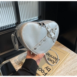 Détail du sac argenté en forme de cœur avec rivets punk et boucle métallique