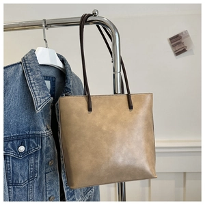 Minimalist leather bucket tote bag in khaki with coffee shoulder straps on a hanger