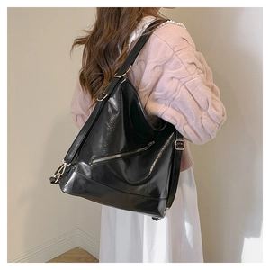 Detalle del bolso tote negro brillante de gran capacidad con herrajes dorados