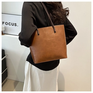 Minimalist vintage brown bucket bag for women shown as a stylish shoulder tote on a model