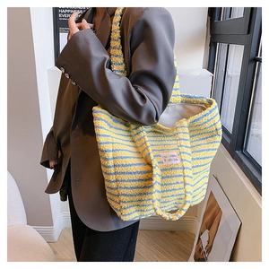 Dettaglio della texture peluche di una borsa tote a righe gialle e blu in ecopelliccia