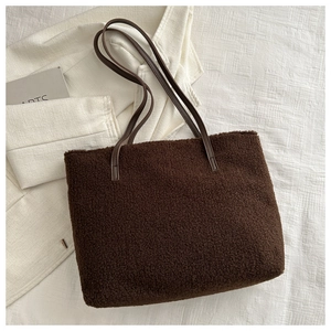 Détail du sac fourre-tout en peluche marron foncé avec anses en cuir sur tissu blanc