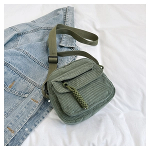 Detail van groene corduroy crossbodytas met verstelbare riem en gestreepte stoftextuur