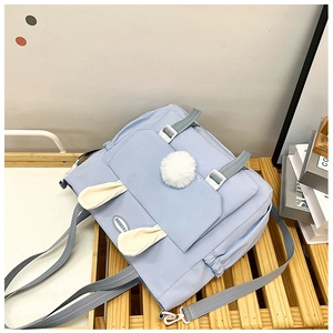 Dettaglio di uno zaino azzurro in nylon con orecchie di coniglio e logo moda