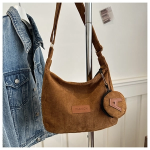 Close-up of brown corduroy crescent bag with adjustable strap and mini round coin purse