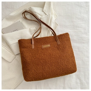 Gros plan du sac fourre-tout en peluche marron avec anses en cuir et étiquette Fashion