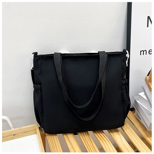 Dettaglio della borsa tote in nylon nero con tasche laterali e robusti spallacci doppi