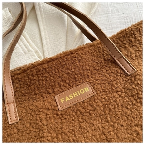 Gros plan d'un sac cabas en peluche caramel avec étiquette FASHION et anse en cuir