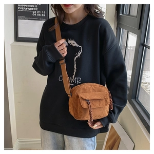 Detail van donkerbruine corduroy crossbodytas met geweven trekker aan de ritssluiting