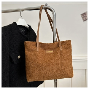 Détail d'un sac cabas en peluche marron, texture peau de mouton et étiquette FASHION