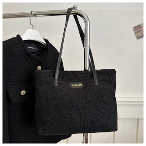 Detalle del bolso tote negro de lana de cordero con etiqueta y correas de cuero