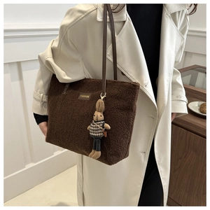Vue détaillée de la texture peluche avec plaque Fashion et anses en cuir du sac cabas