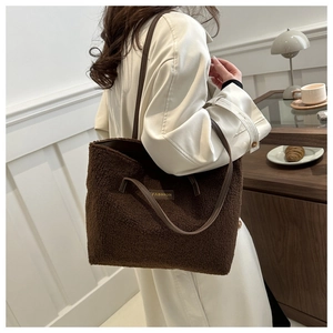 Détail du sac fourre-tout en peluche marron doux avec sangle en cuir et étiquette tendance